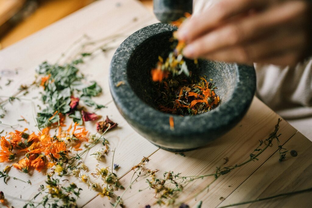 Aromatic dried herbs being crushed in a stone mortar for culinary or medicinal use.